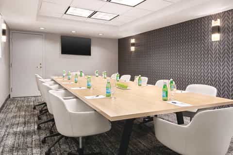 Modern conference room with long wooden table, white chairs, and patterned accent wall