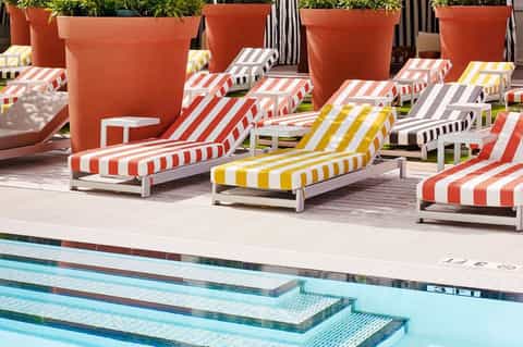 Colorful striped lounge chairs arranged around an outdoor swimming pool with large terracotta planters