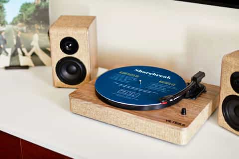 Wooden turntable with blue vinyl record and matching cork speakers on white surface
