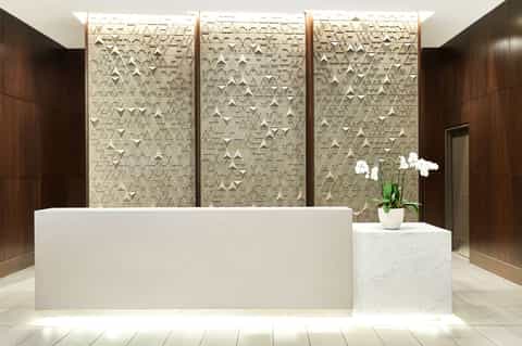 Modern hotel lobby with white marble reception desk and textured wall panels
