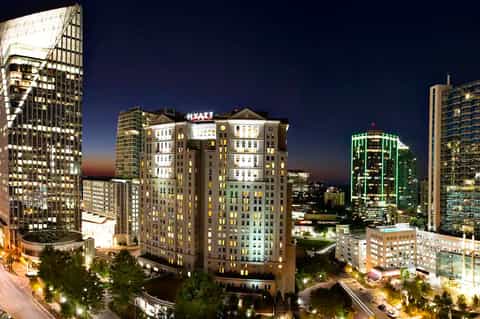 Hyatt hotel illuminated at night in downtown cityscape surrounded by tall office and residential buildings