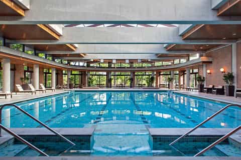 Indoor Olympic-size swimming pool with lane markings, brick architecture, and large windows overlooking grounds
