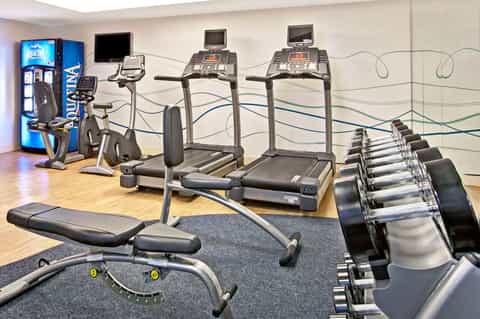 Fitness center with treadmills, exercise bikes, dumbbells, and workout equipment on wooden flooring