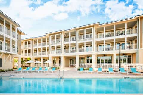 Modern beachfront resort with cream and white multi-story building and turquoise lounge chairs
