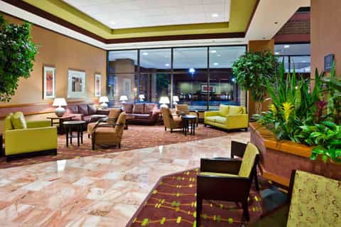 Hotel lobby with lime green ceiling, brown leather seating, marble floors, and potted plants