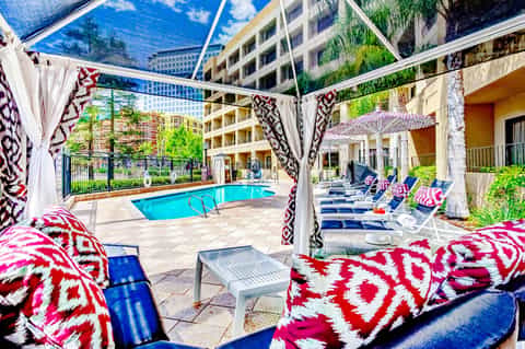Elegant poolside seating area with geometric patterned cushions and shaded pergola