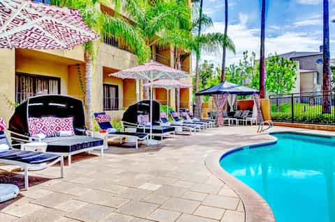 Resort pool area with cabanas, umbrellas, and yellow buildings surrounded by palm trees