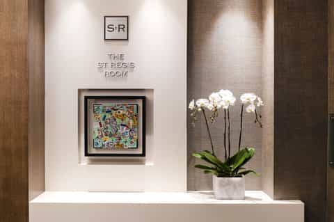 Elegant hallway entrance to St Regs Room with white orchids and modern wall art