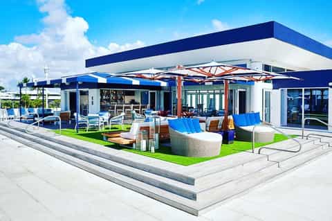 Modern rooftop bar with blue umbrellas, lounge seating, and ocean views