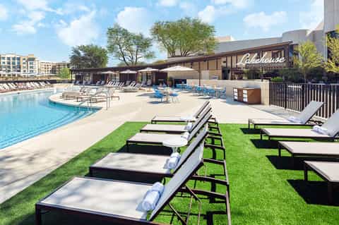 Lakehouse Waterfront Lounge pool area with lounge chairs, lawn seating, and waterside building