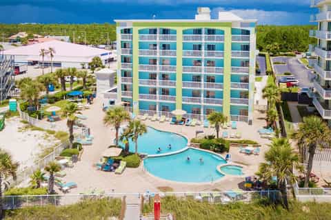 Aerial view of colorful beachfront resort with multiple pools and palm trees