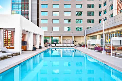 Resort courtyard with rectangular pool, white cabanas, and tall residential building in background