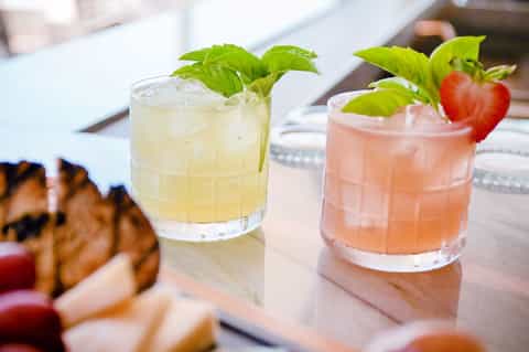 Two refreshing cocktails with fresh mint and strawberry garnish on white counter