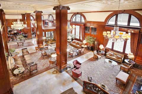 Elegant hotel lobby with ornate wood columns, arched windows, and vintage furnishings