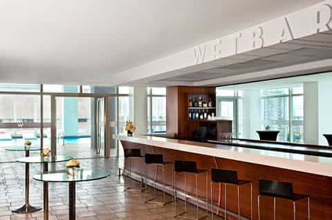 Modern hotel wet bar with wood paneling, wine display, and ocean view windows