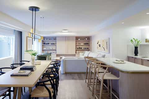 Modern open-concept living space with dining table, kitchen bar, sofa, and built-in shelving