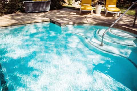 Sparkling turquoise hot spring pool with natural mineral waters and wooden deck surrounded by landscaping