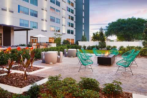 Modern courtyard with turquoise chairs, fire pit, and contemporary hotel building