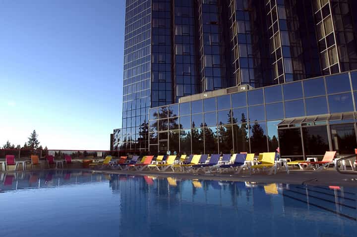 Modern resort pool with colorful lounge chairs against glass high-rise hotel building in daylight