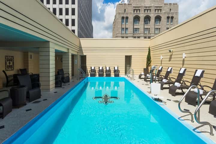 Indoor lap pool with lounge chairs, urban courtyard setting surrounded by tall buildings