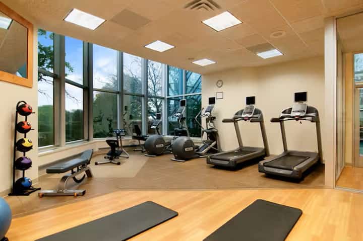 Fitness center with treadmills, exercise equipment, large windows, wooden flooring, and natural light