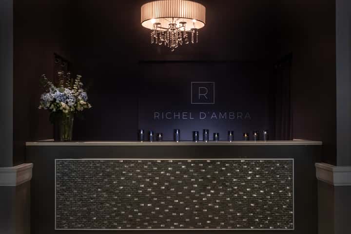 Luxury spa reception desk with dark brick detail, elegant chandelier, and flower arrangement