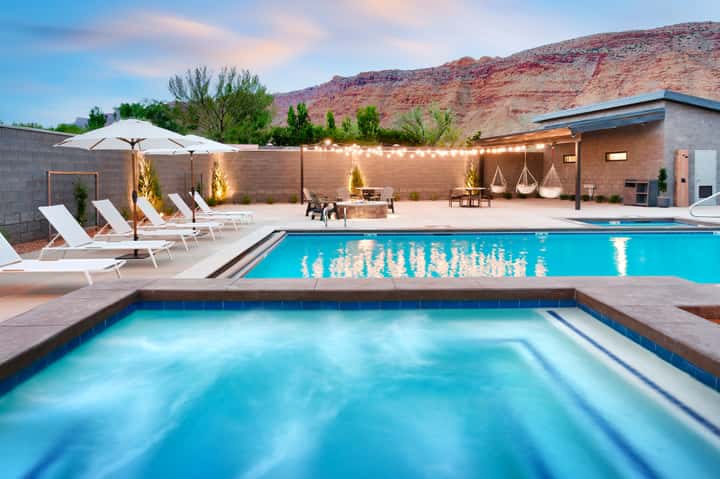 Resort pool area with loungers, fire pit, and desert mountains at dusk