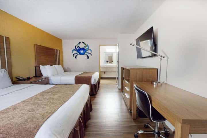 Hotel room with two queen beds, yellow accent wall, and en-suite bathroom