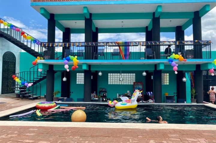 Colorful resort pool with turquoise structure, rainbow decorations, and guests enjoying water activities