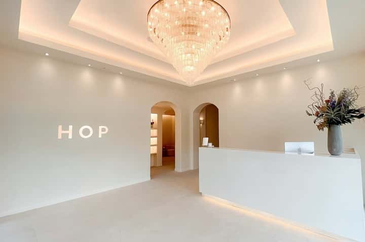 Minimalist hotel reception area with white walls, crystal chandelier, and HOP signage