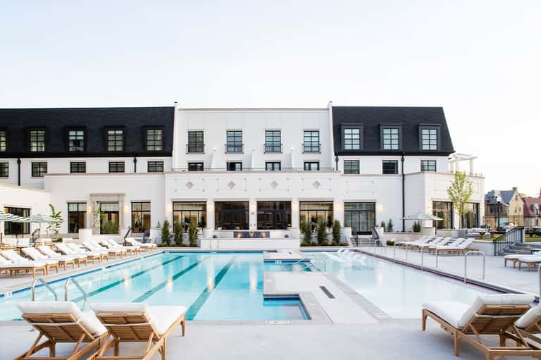 Modern white resort with lap pool, lounge chairs, and manicured grounds
