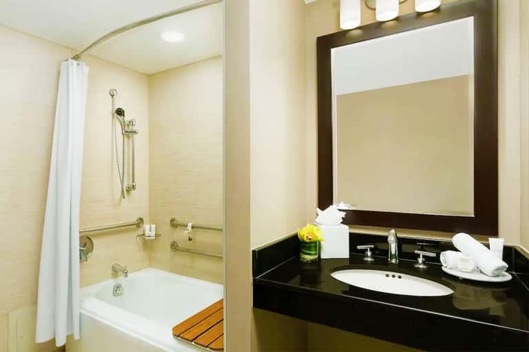 Modern bathroom with black vanity, vessel sink, large mirror, and tiled shower