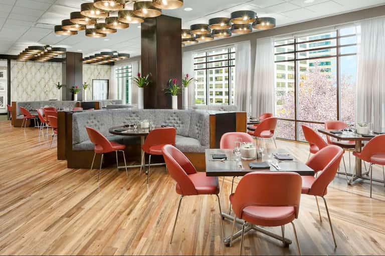 Modern upscale restaurant with gold pendant lights, red chairs, wood flooring, and city views