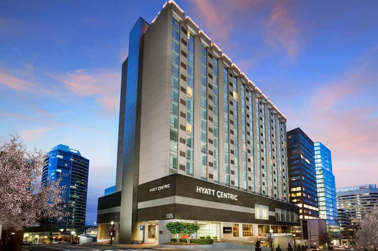 Hyatt Centric hotel exterior at dusk with illuminated signage and surrounding city buildings