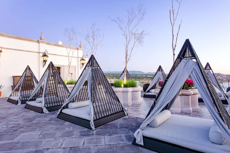 Outdoor terrace with pyramid-shaped loungers and white drapes overlooking valley landscape