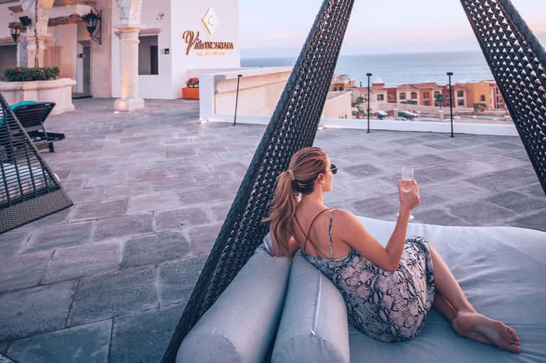 Woman relaxing in hammock with wine glass overlooking coastal Mediterranean resort