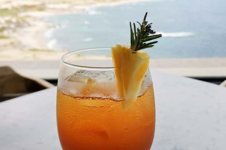 Tropical cocktail with pineapple garnish overlooking beach and ocean