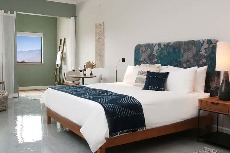 Luxury hotel bedroom with green accent wall, teal headboard, and mountain view
