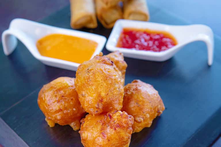 Golden fried pastries with dipping sauces on a blue plate