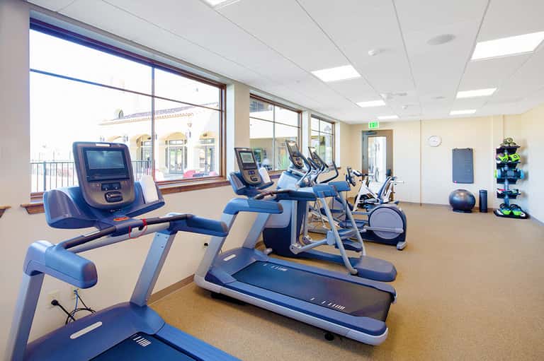 Modern fitness center with treadmills, stationary bikes, and exercise equipment with ocean views