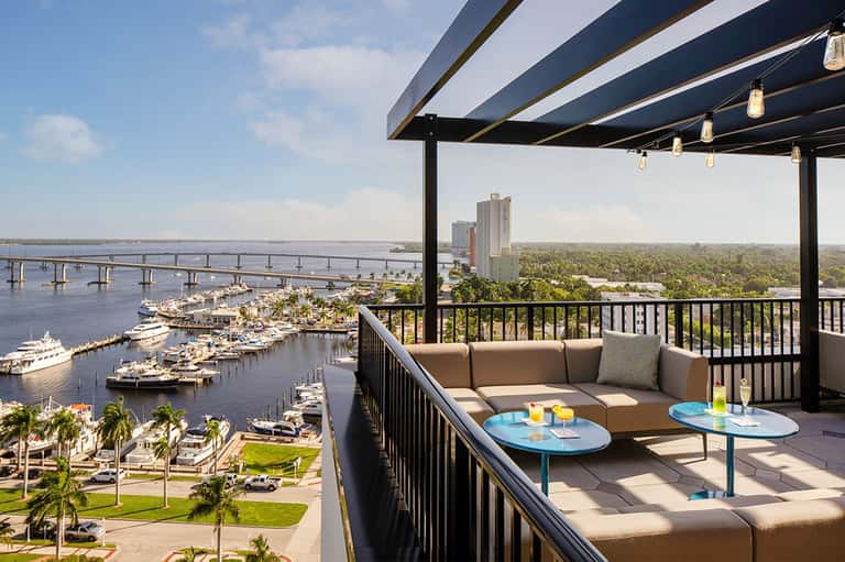 Elevated lounge area overlooking marina with boats, bridge, and waterfront cityscape views