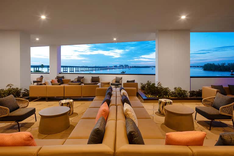 Elegant lounge with orange seating, geometric design, and waterfront views through large windows