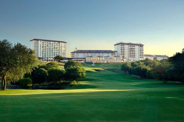 Golf course with hotel buildings and manicured lawns at golden hour