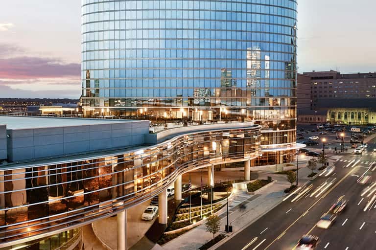 Contemporary glass building at dusk with curved architecture and illuminated ground level