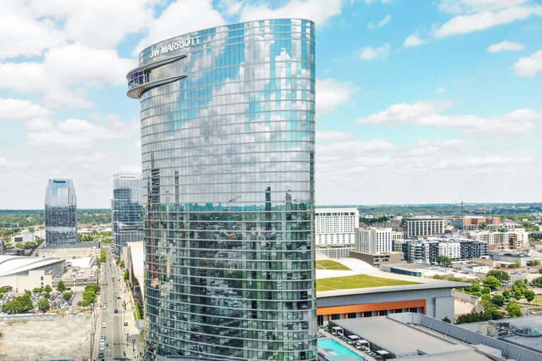 Circular tower hotel with JW Marriott signage overlooking cityscape and rooftop pool