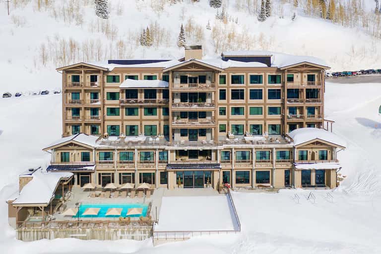 Aerial view of large luxury resort hotel surrounded by snowy landscape with frozen lake nearby
