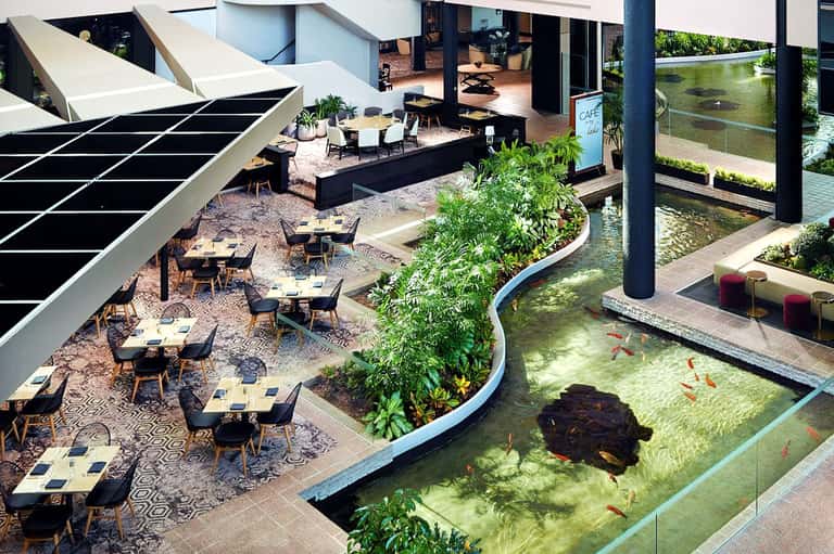 Modern resort courtyard with dining tables, living green wall, koi pond, and contemporary architecture