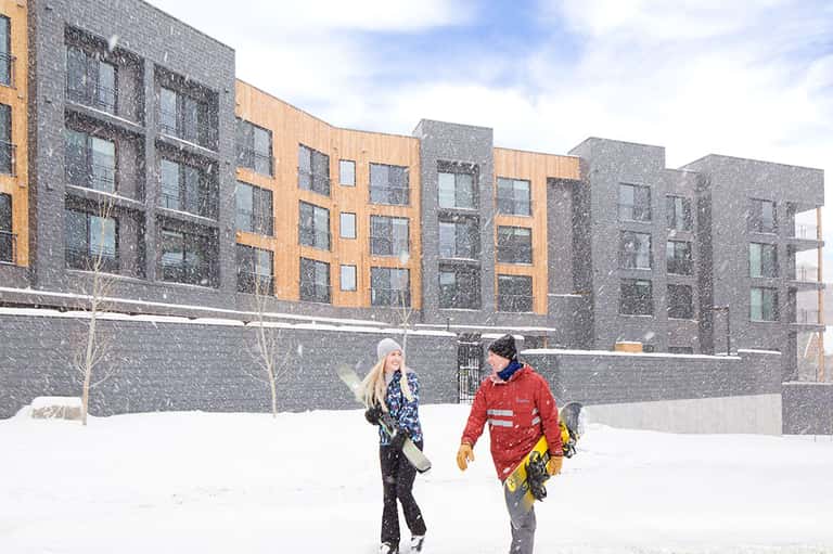 Modern apartment buildings with mixed brick and stone facades in snowy winter landscape