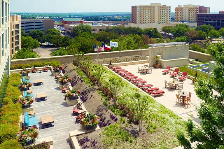 Rooftop terrace with lounge chairs, umbrellas, and city skyline view with river in background