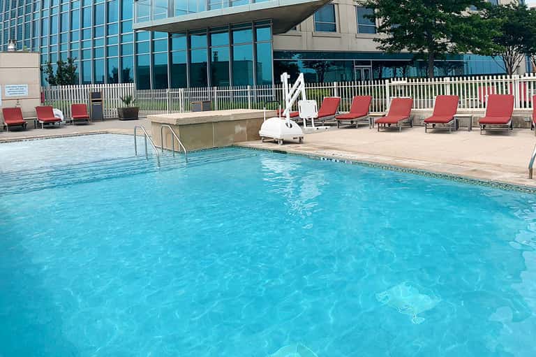 Resort outdoor pool with red lounge chairs and glass balcony railing